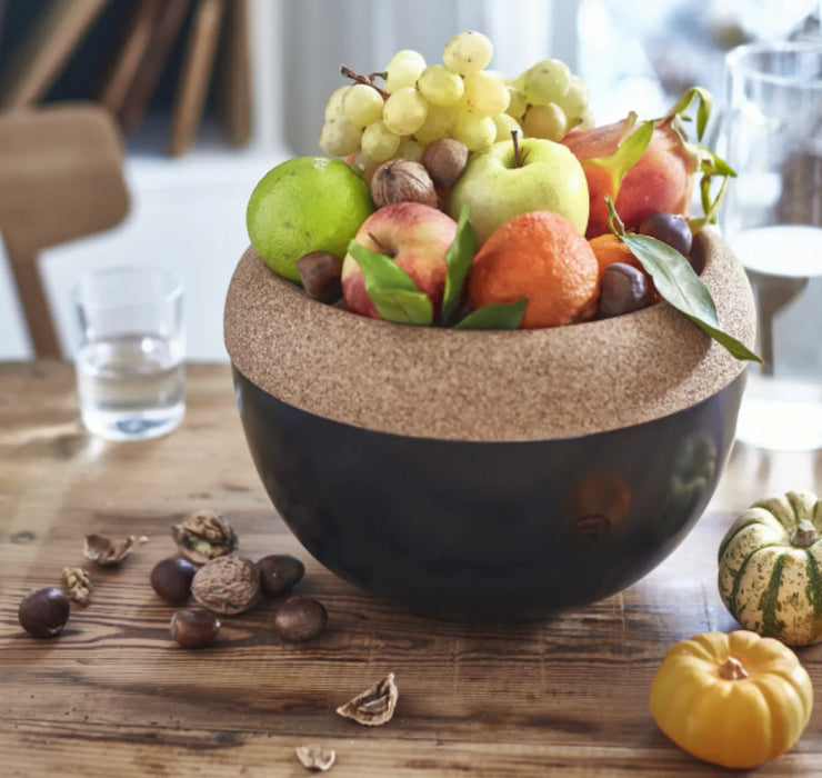 Deep ceramic storage bowl with cork lid, filled with assorted fresh fruit and nuts on a wooden table