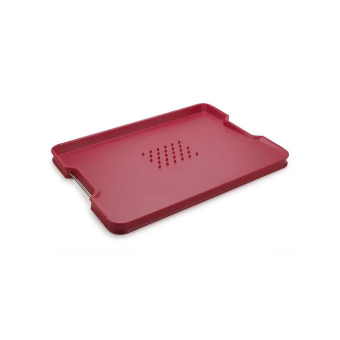 Red large kitchen cutting board with raised edges and juice-draining holes on white background