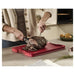 Person slicing roast beef on a large red carving board in a modern kitchen setting