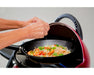 Person cooking stir fry with prawns and vegetables on a portable single burner BBQ grill